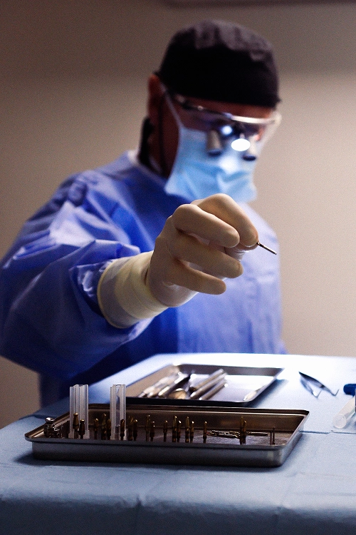 Dentiste qui manipule un implant dentaire